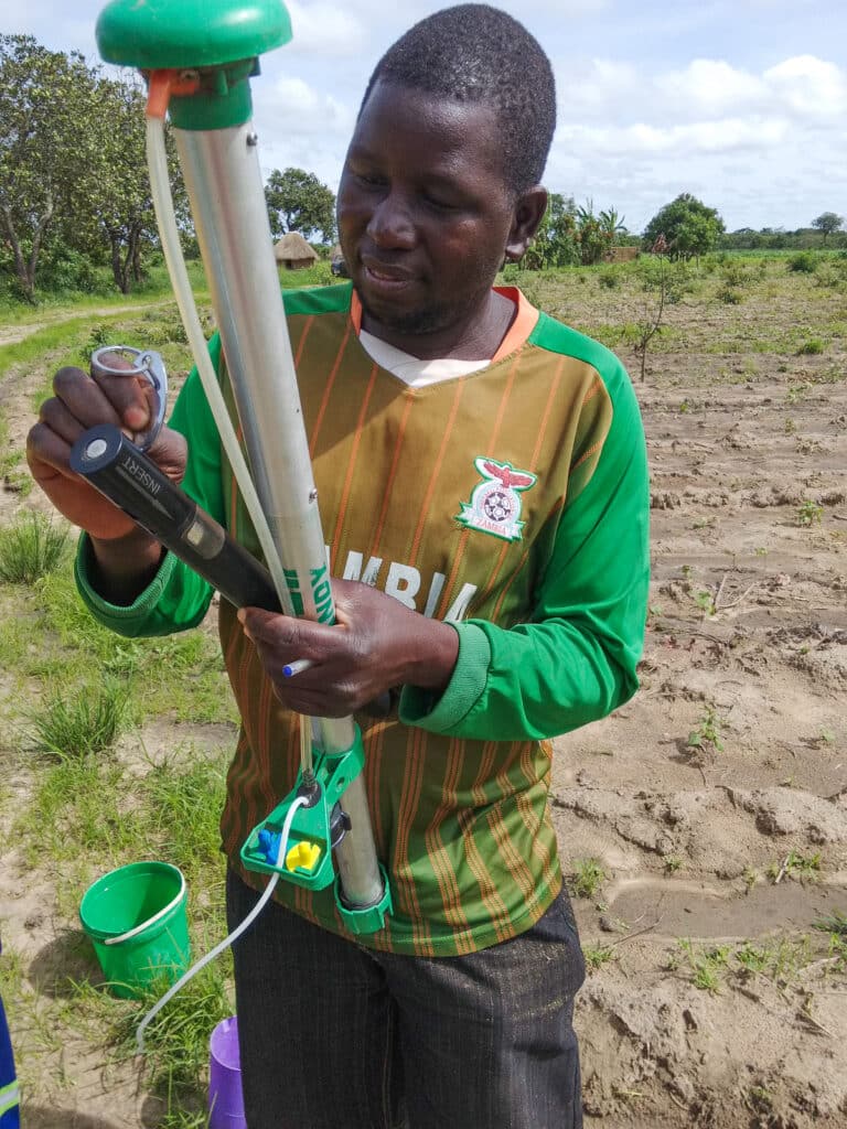 En småskala bomullsbonde fra Zambia klargjør sin Solar Battery Stick og sprøyte klar for å kunne sprøyte åkeren. FOTO: Solar Village